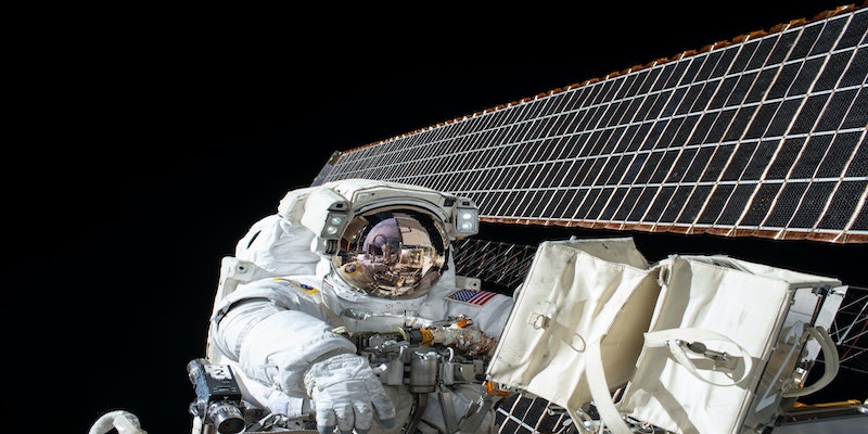 astronaut in space beside satellite