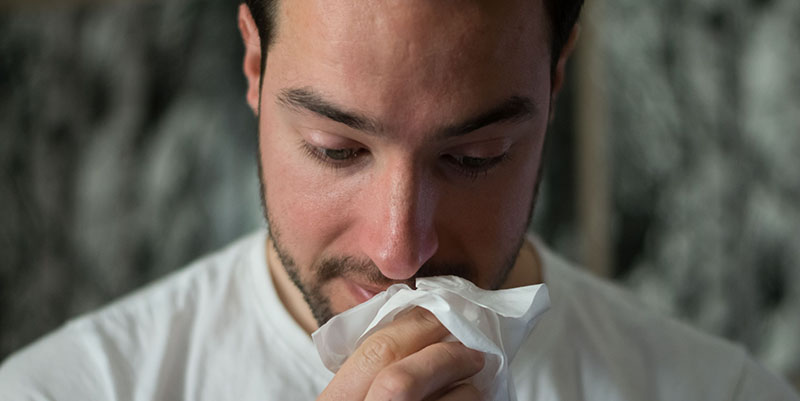 Man holding tissue to his face
