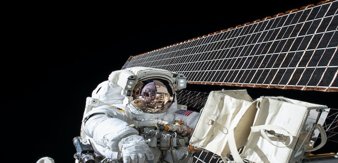 astronaut in space beside satellite