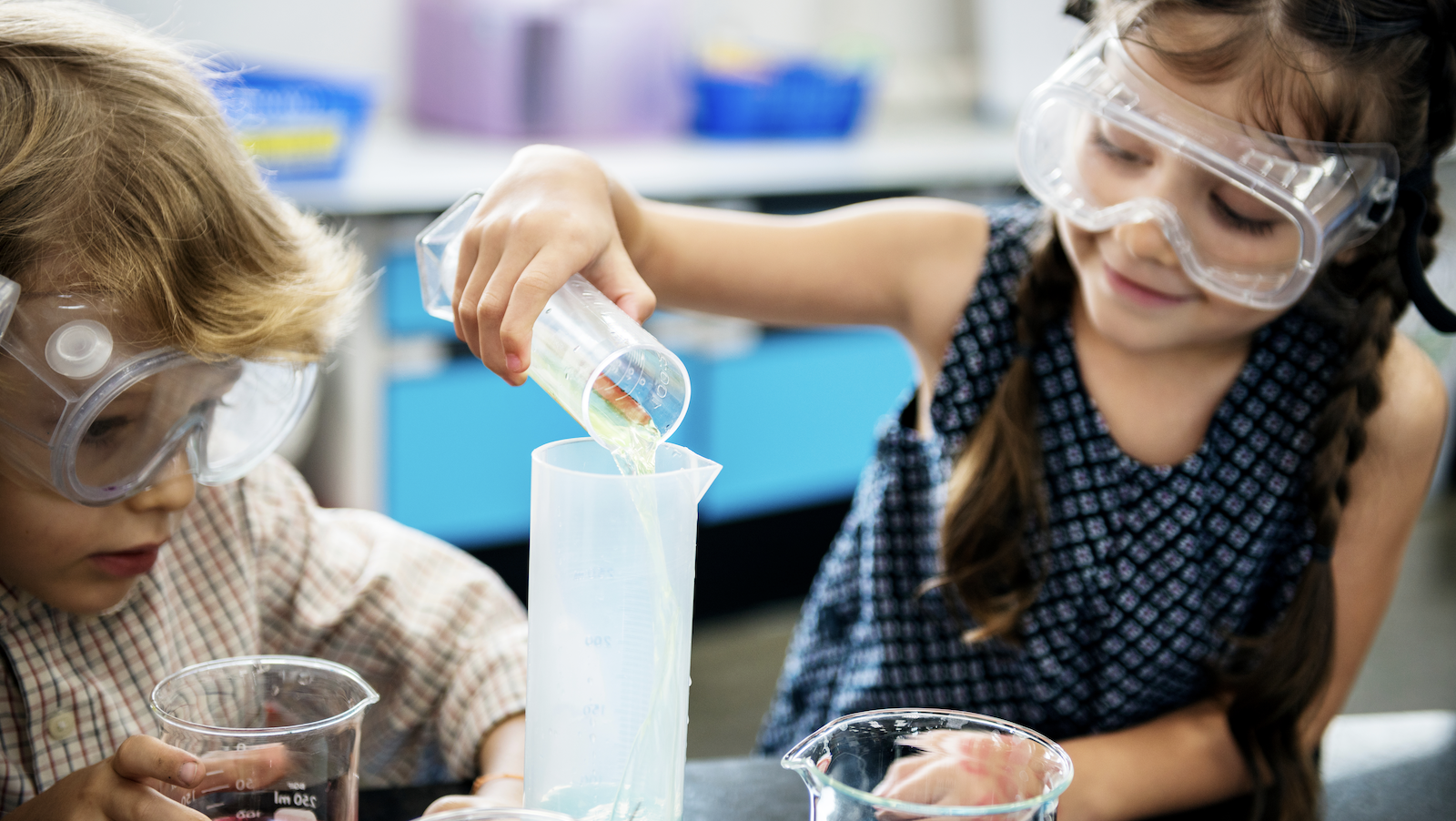 Boy and girl pouring a liquid into a beaker