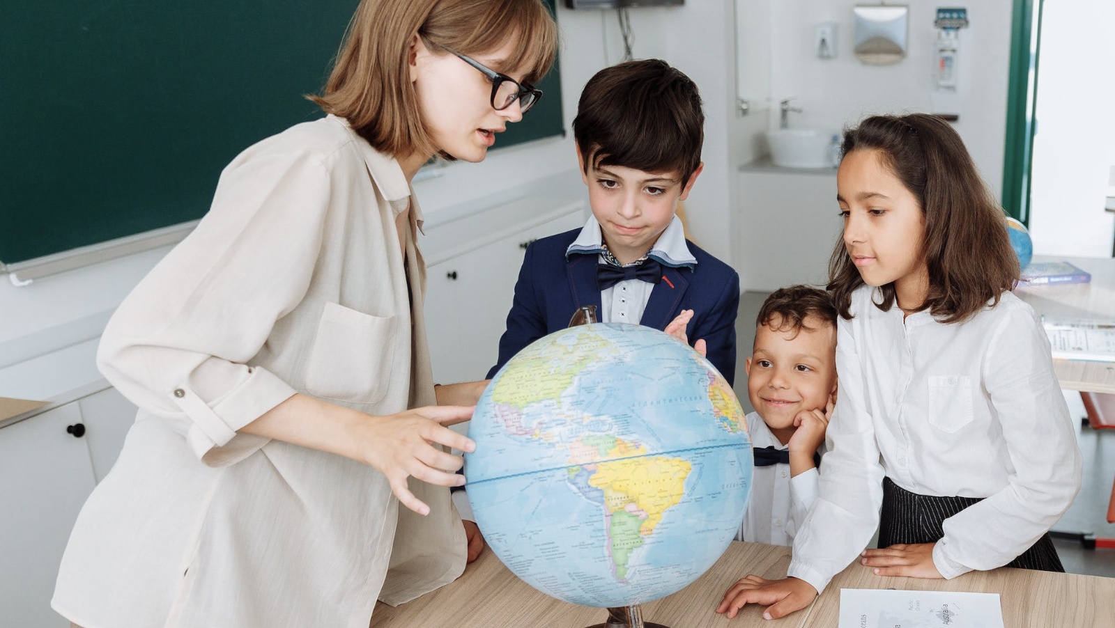 Students and teacher looking at a globe